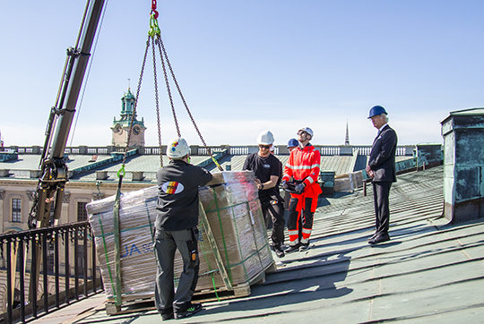 Kungen var på plats på Stockholms slotts tak när några av paketen med solcellspaneler lyftes upp med hjälp av en kranbil från Inre borggården. 