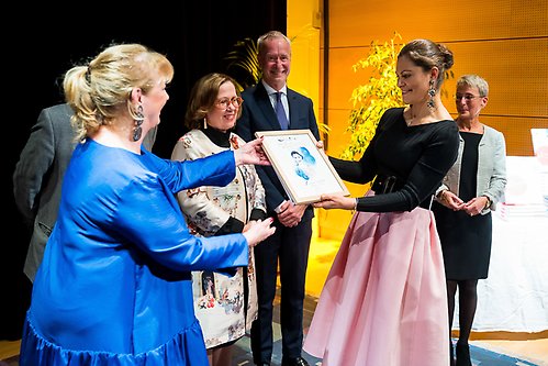 The Crown Princess accepts a painting and the anniversary book 'Amitié' about the Swedish Institute's 50-year history, illustrated by Stina Wirsén. 